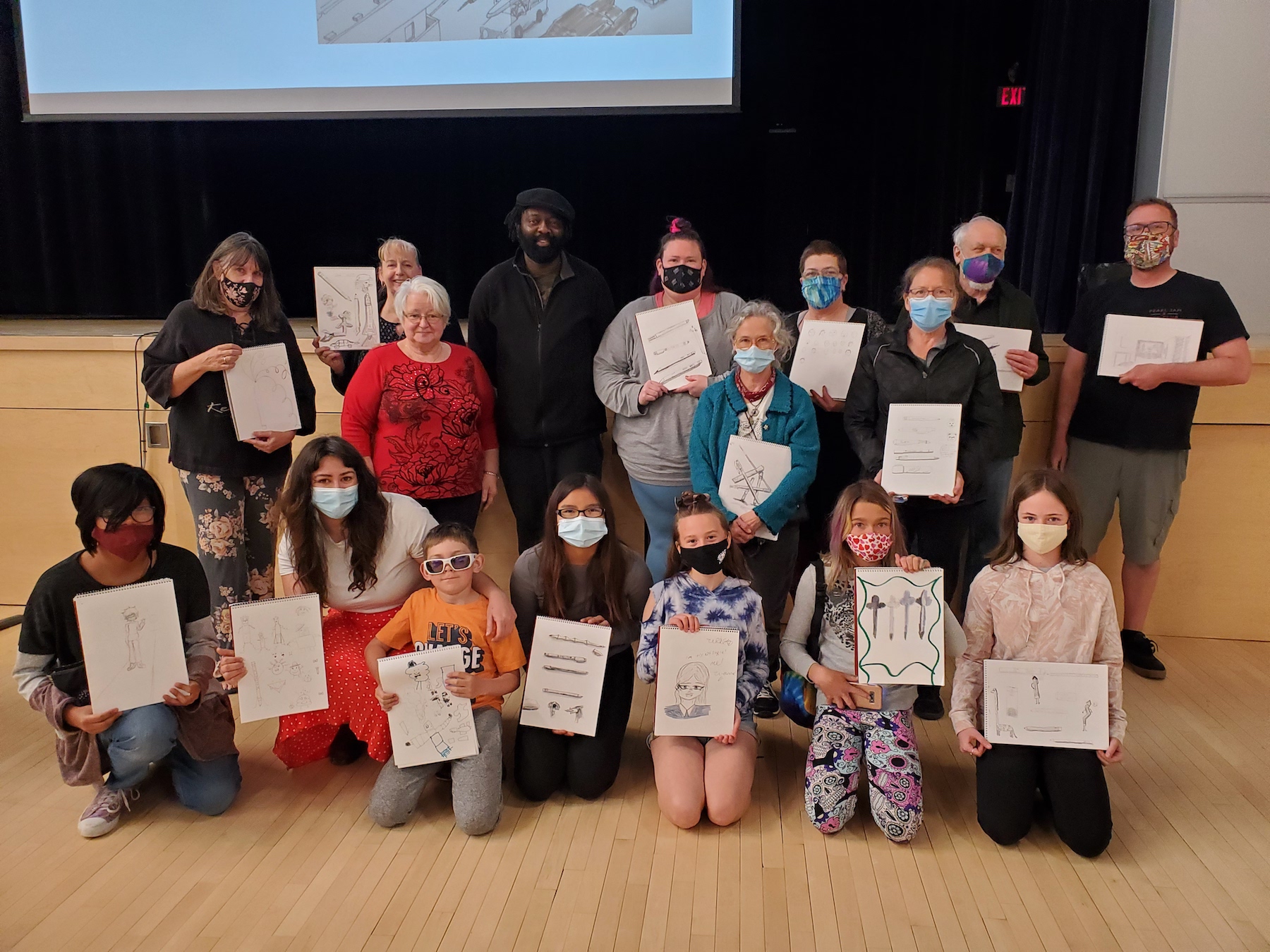 Groups shot of people holding up pictures they've drawn.