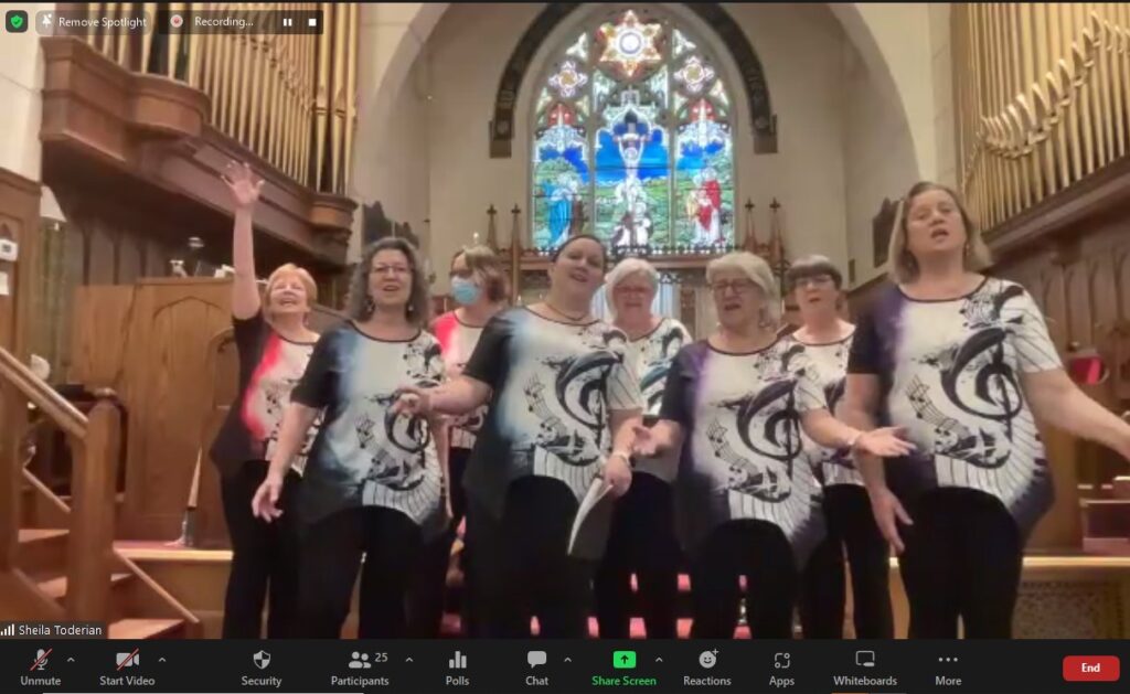 Group of women in matching t-shirts singing enthusastically.