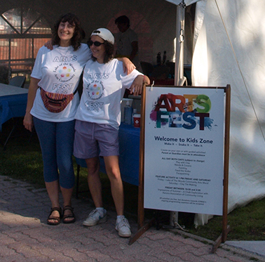Aimee Baldwin and Everette Fournier beside ARTSFEST poster