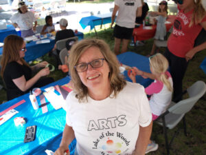 Woman with shoulder length blonde hair wearing an ArtsFest t-shirt smiling at camera. 