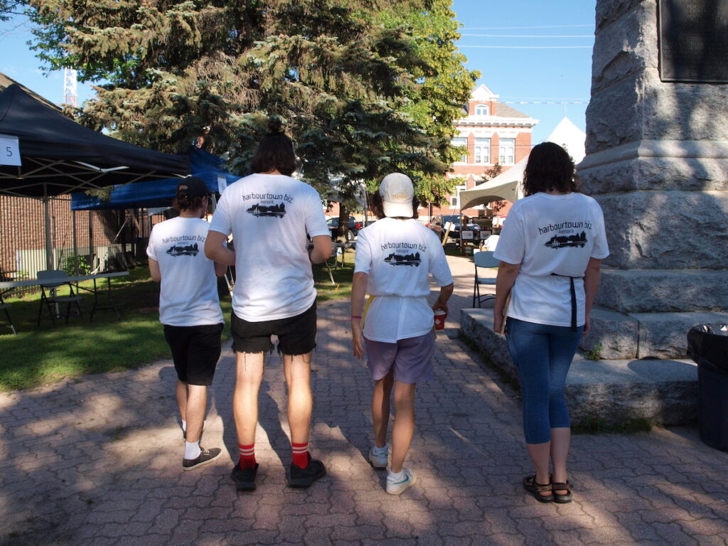Four people with backs to camera and Harbourtown Biz on backs of t-shirts.