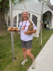 Woman in ArtsFest t-shirt holding a plate of muffins.