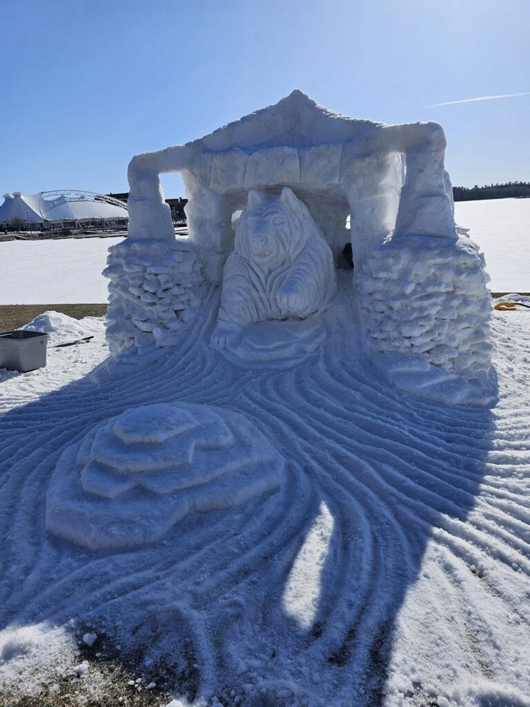 A building carved in snow with animals in each entrance. 