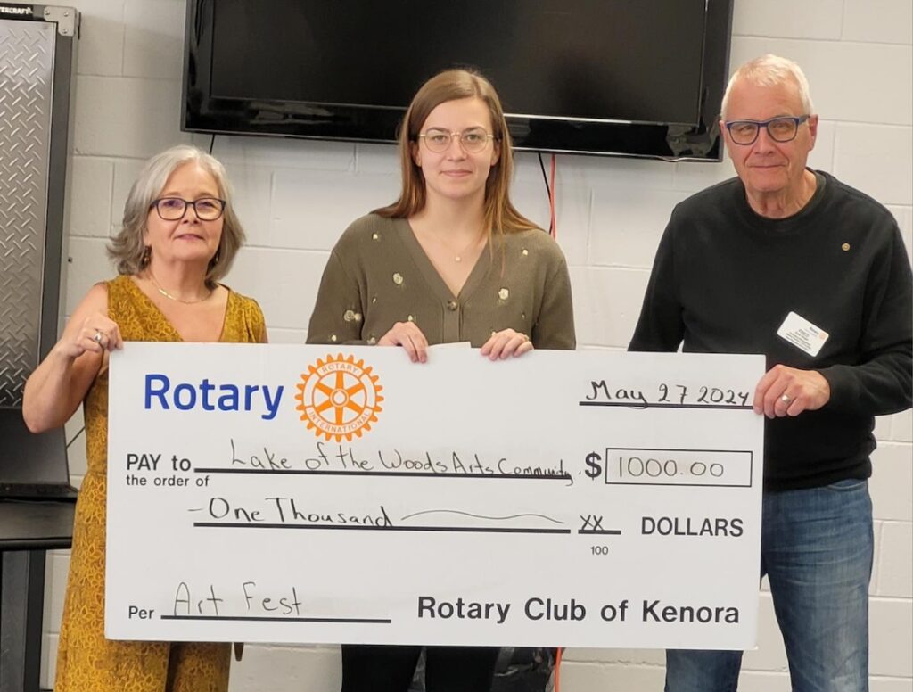 Three people holding up a large $1,000 displaying the Rotary logo.