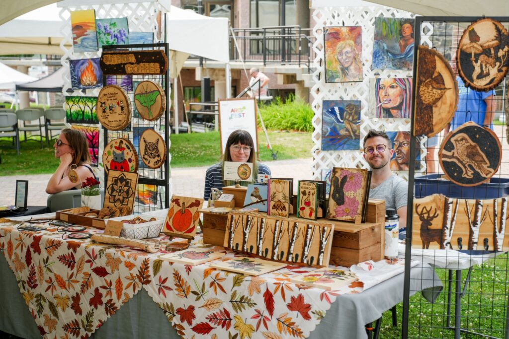 Woman and man sitting behind a table with wood art display.